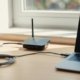 Small black hotspot device with antenna connected to a laptop by USB cable